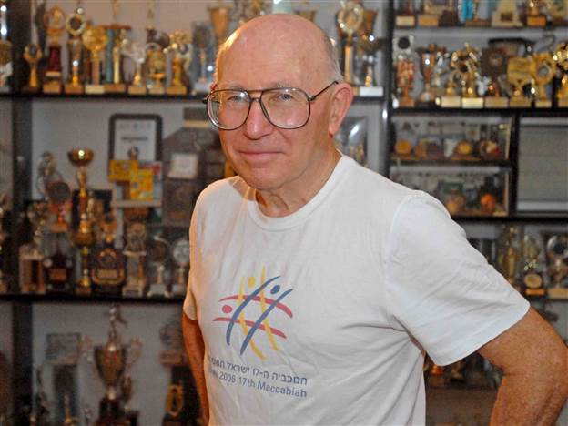 על רקע ארון הגביעים בביתו (צילום ארכיון: דני מכליס, אוניברסיטת בן-גוריון בנגב)