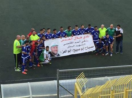 שחקני הילאל אל קוץ עם כרזת המחבל (פייסבוק)