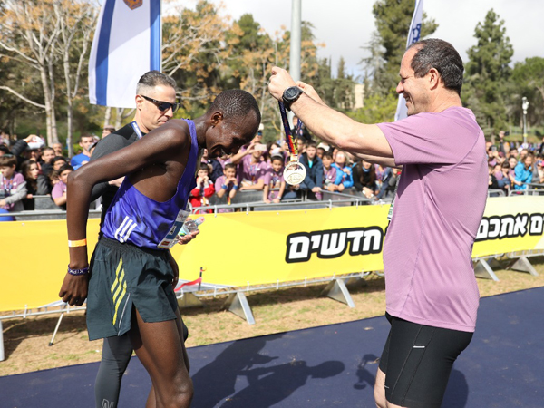 שדראק מקבל את המדליה מברקת (באדיבות מרתון ירושלים)