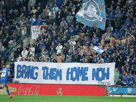 בדקה השביעית, אוהדי הפועל פ``ת הפסיקו לעודד ובמשך דקות מחאו כפיים והניפו שלט להחזרת החטופים (אלן שיבר)